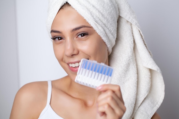 Zdrowa kobieta z białymi zębami używa szczotek do czyszczenia przestrzeni międzyzębowych