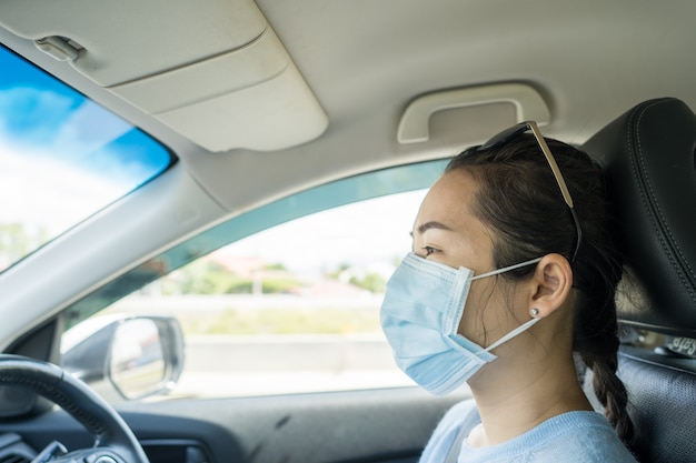 Zdrowa kobieta z ochronną maską na twarz prowadząca samochód