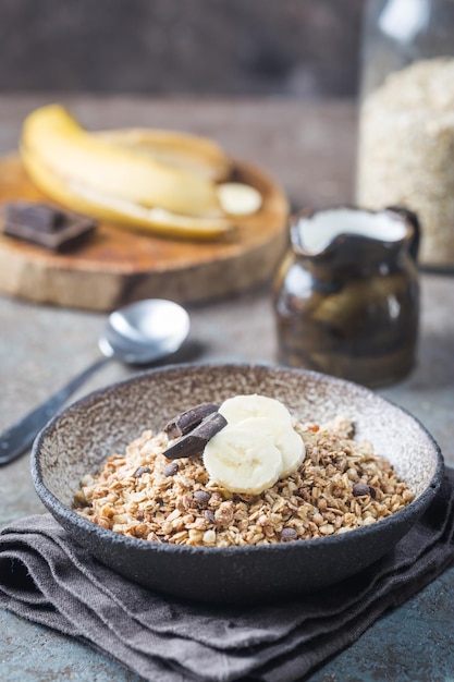 Zdrowa miska śniadaniowa. Granola z czekoladą i bananem na białym drewnianym stole. Pojęcie zdrowego żywienia i diety.