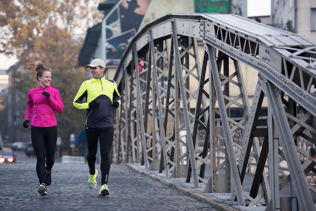 zdrowa młoda para jogging w mieście wczesnym rankiem ze wschodem słońca w tle