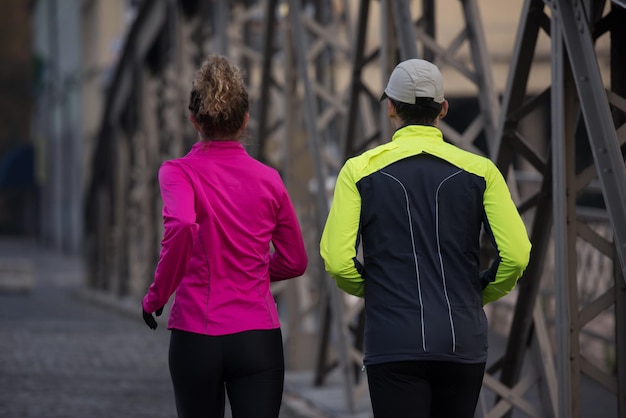 zdrowa młoda para jogging w mieście wczesnym rankiem ze wschodem słońca w tle