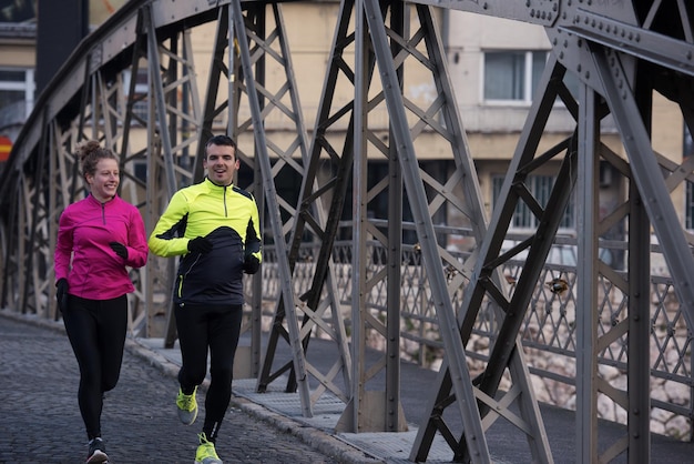 zdrowa młoda para jogging w mieście wczesnym rankiem ze wschodem słońca w tle