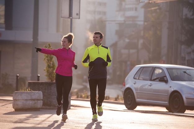 zdrowa młoda para jogging w mieście wczesnym rankiem ze wschodem słońca w tle