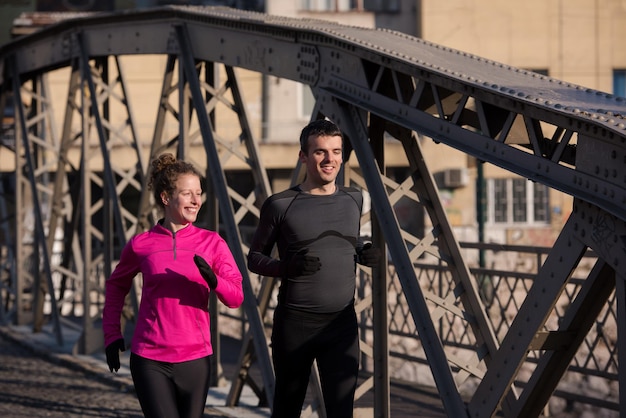 zdrowa młoda para jogging w mieście wczesnym rankiem ze wschodem słońca w tle