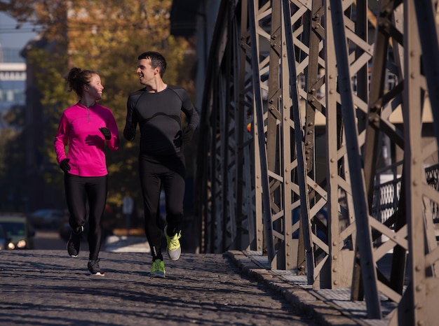 zdrowa młoda para jogging w mieście wczesnym rankiem ze wschodem słońca w tle