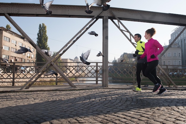 Zdjęcie zdrowa młoda para jogging w mieście wczesnym rankiem ze wschodem słońca w tle