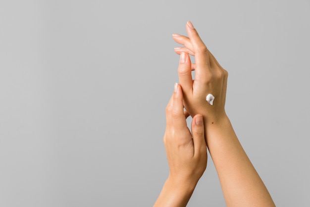 Zdrowe dłonie młodej kobiety stosujące krem do opalania