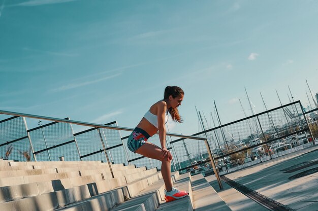Zdrowe nawyki. Pełna długość pięknej młodej kobiety w sportowej odzieży relaksującej podczas ćwiczeń na świeżym powietrzu