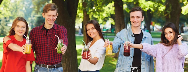 Zdrowe odżywianie. Grupa przyjaciół pije detox świeżego soku na zielonym tle przyrody.