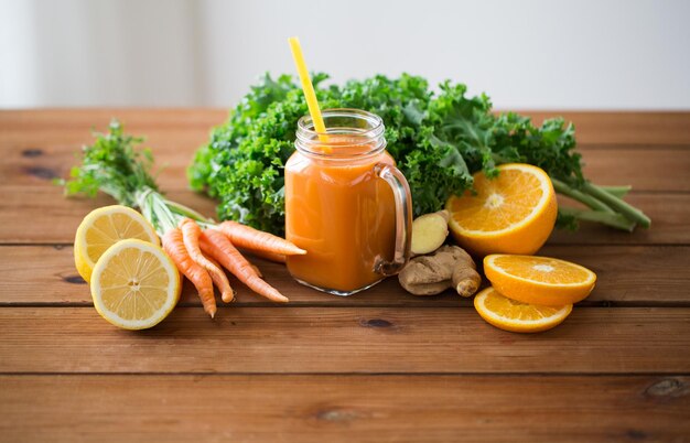 zdrowe odżywianie, jedzenie, dieta i koncepcja wegetariańska - szklany dzbanek soku z marchwi, owoców i warzyw na drewnianym stole