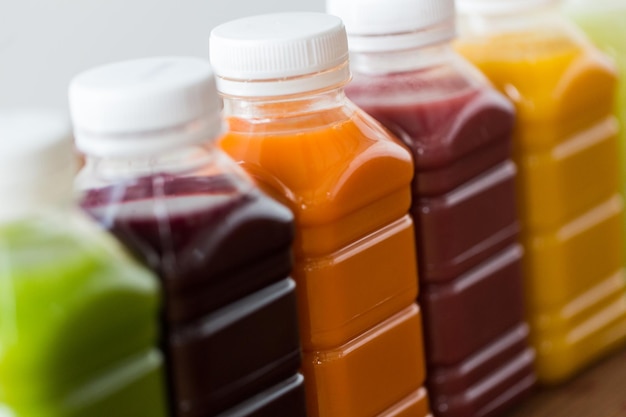 zdrowe odżywianie, napoje, dieta i koncepcja detoksykacji - zbliżenie plastikowych butelek z różnymi sokami owocowymi lub warzywnymi