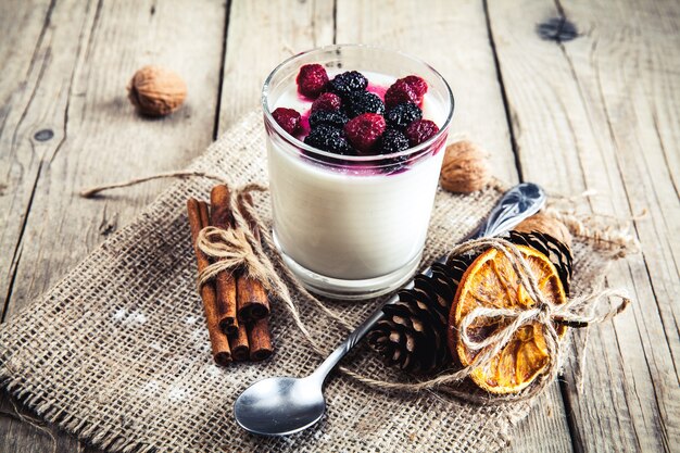 Zdrowe śniadanie - jogurt mleczny z malinami, morwy na drewnianej powierzchni