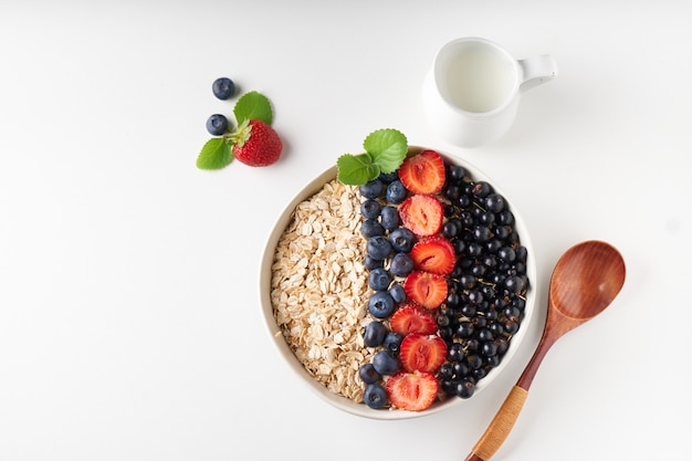 Zdrowe śniadanie, muesli z porzeczkami, jagodami i truskawkami serwowane w chlebie na jasnej powierzchni