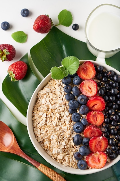 Zdrowe śniadanie, muesli z porzeczkami, jagodami i truskawkami serwowane w chlebie na jasnej powierzchni