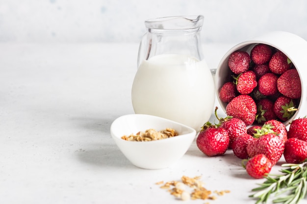 Zdrowe śniadanie składników. Domowa granola, mleko lub jogurt w dzbankach, truskawkach i rozmarynie