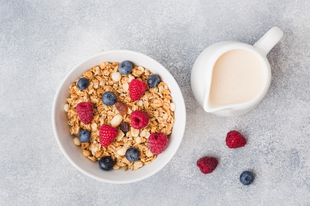 Zdrowe śniadanie. Świeży granola, musli z jogurtem i jagody na szarym tle.