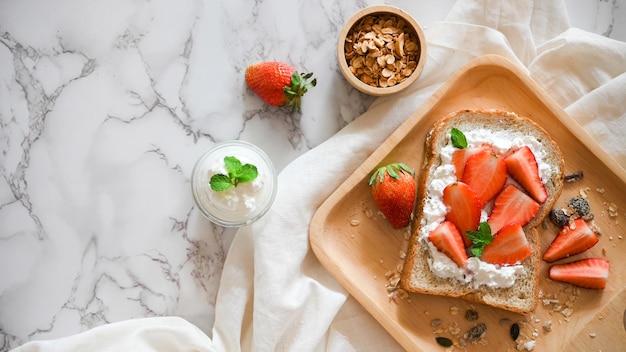 Zdrowe śniadanie Truskawkowe tosty z twarogiem i muesli na marmurowym tle stołu