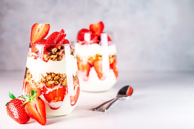 Zdrowe śniadanie z parfaitów truskawkowych ze świeżym jogurtem truskawkowym i musli w szklankach