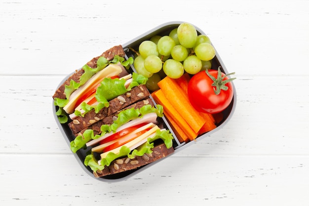 Zdrowe szkolne pudełko na lunch z kanapką i świeżymi warzywami