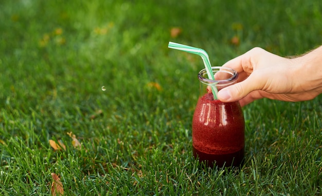 Zdrowy czerwony napój detox w ręku. Słoik na koktajl ze świeżych buraków na zewnątrz.