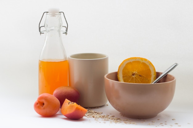 zdrowy kubek śniadaniowy z płatkami, owocami i sokiem na białej powierzchni