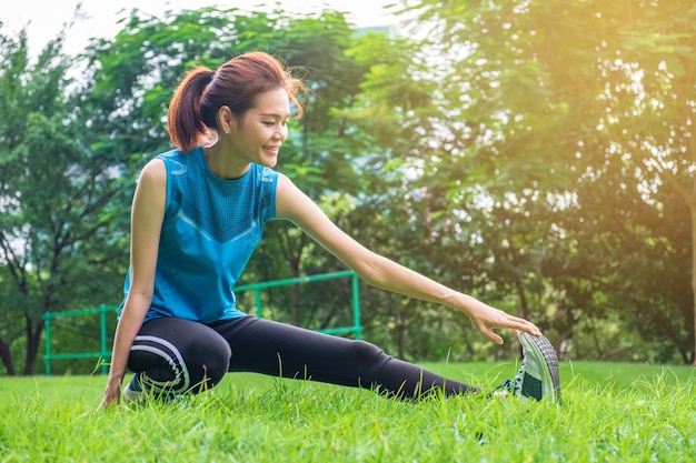 Zdrowy młody Azja kobiety biegacz rozgrzewkowy przed biegać przy parkiem outdoors