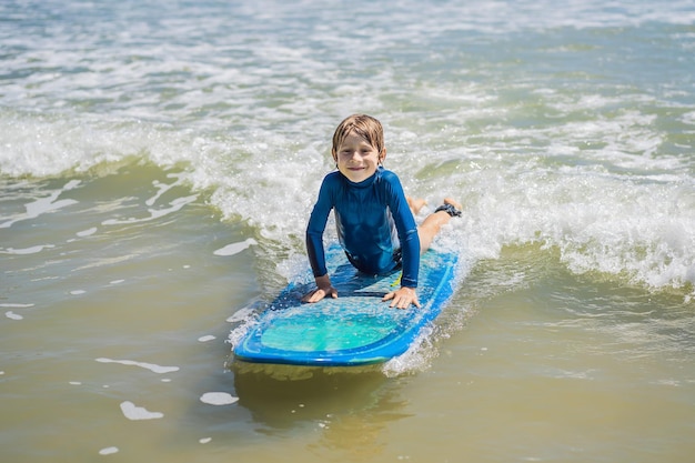 Zdrowy młody chłopak uczy się surfować w morzu lub oceanie