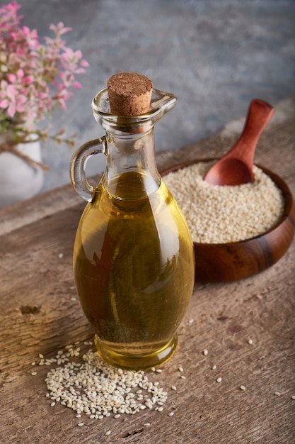 Zdrowy olej sezamowy w szklanej butelce i sezamu na drewnianym stole Vertical