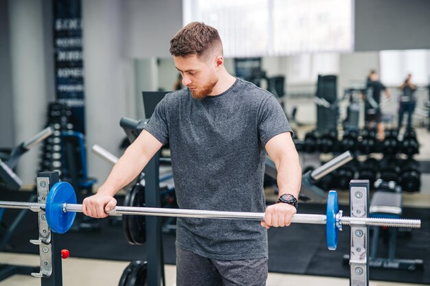 Zdrowy przystojny młody trener pracujący na siłowni. Fitness atrakcyjny mężczyzna trening na siłowni.