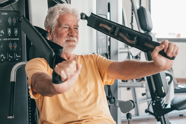 Zdrowy starszy mężczyzna wykonuje ćwiczenia w siłowni, aby wzmocnić mięśnie ramienia Sport zdrowie siłownia wellness