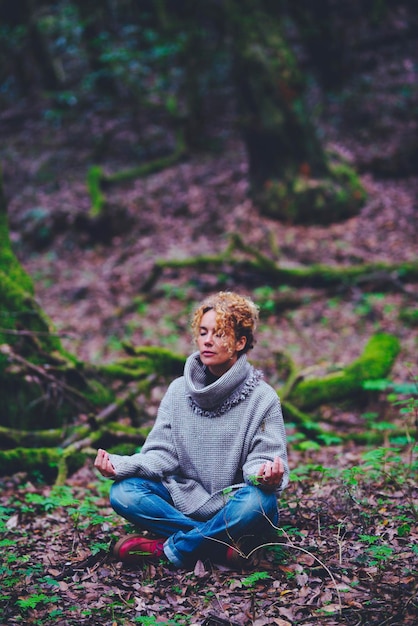 Zdrowy styl życia kobieta siedzi na ziemi w pozycji jogi lotosu z zielonym lasem Natura lasy wokół Kobiety i zen medytacja aktywność wypoczynek na świeżym powietrzu Połączenie ludzi i przyrody
