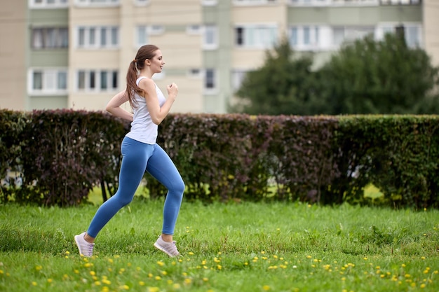 Zdrowy styl życia na osiedlu kobieta z kamienicy na obrzeżach miasta biega w parku