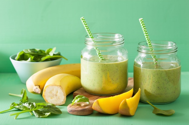 Zdrowy zielony koktajl ze szpinakiem mango-bananem w szklanych słoikach