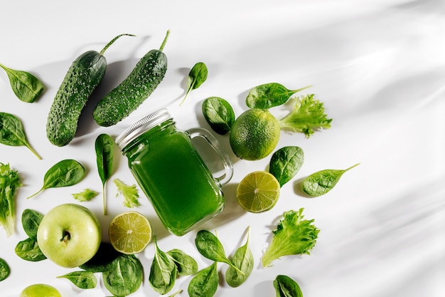 Zdrowy zielony sok warzywny ze szpinakiem i zielonymi owocami i warzywami na białym stole.