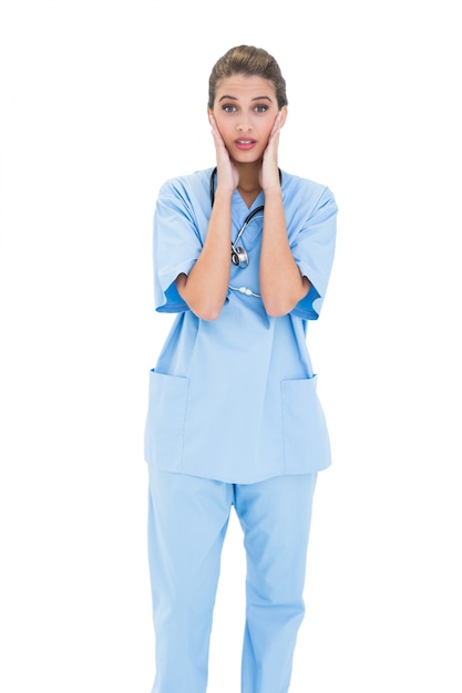 Zdumiewająca brązowowłosa pielęgniarka w błękitnych pętaczkach pozuje z głową w rękach