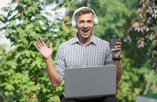 Zdumiony biznesmen w słuchawkach biznesmen freelancer dojrzały biznesmen słuchaj książki audio