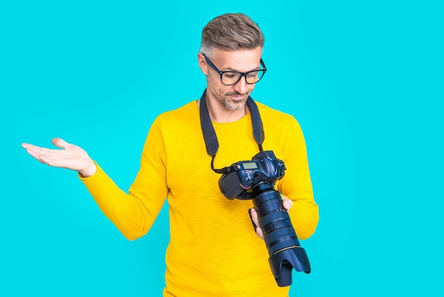 Zdumiony mężczyzna fotograf z aparatem fotograficznym w studio Mężczyzna fotograf z aparatem fotograficznym na tle