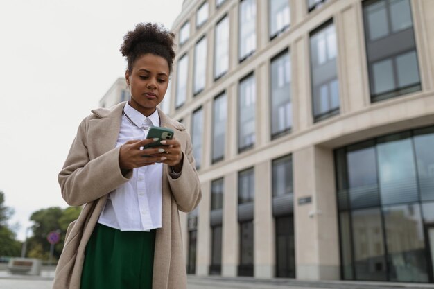 Zdziwiona roczna afroamerykańska bizneswoman zagląda do telefonu komórkowego na tle