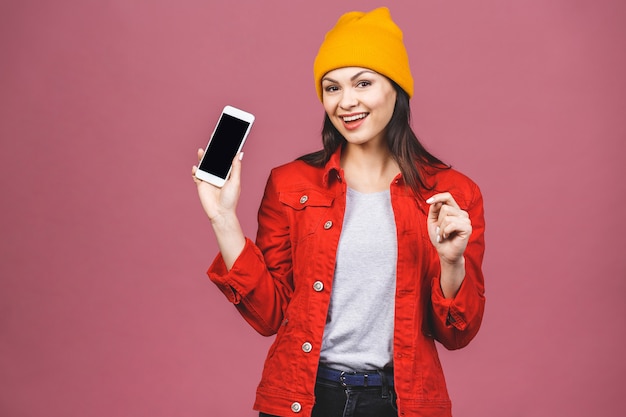 Zdziwiona szczęśliwa brunetki kobieta w przypadkowym pokazuje pustym smartphone