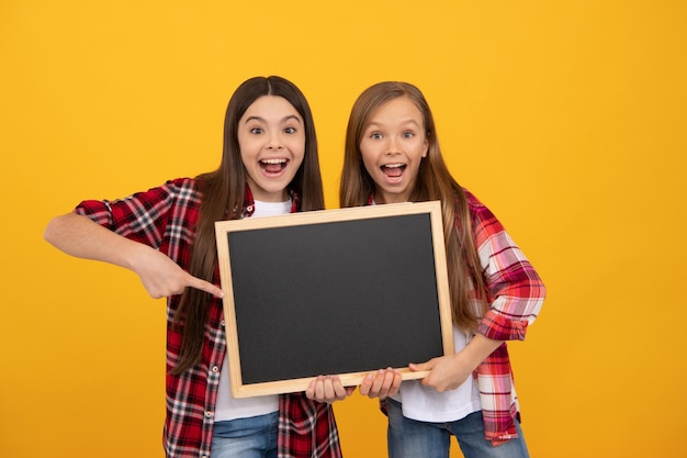 Zdziwione dzieci w swobodnym palcu w kratkę na szkolnej tablicy do kopiowania, reklamy