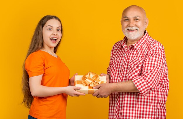 Zdjęcie zdziwione dziecko i dziadek z pudełkiem prezentów na rocznicę