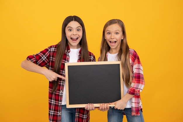 Zdziwione nastolatki w dorywczo kraciastym palcem wskazującym na tablicy szkolnej na miejsce na kopię, reklamę.