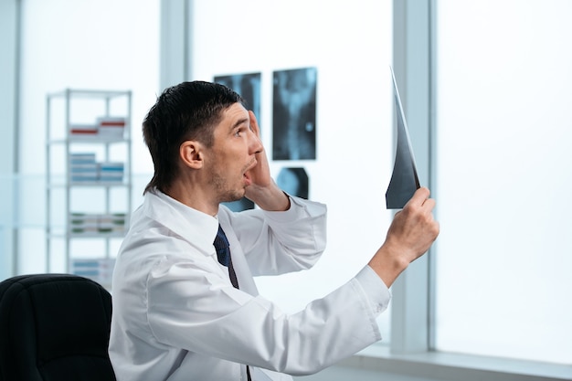 Zdziwiony lekarz patrząc na zdjęcie rentgenowskie pacjenta