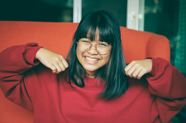 Zębata uśmiechnięta twarz azjatyckiej nastolatka w domu w salonie