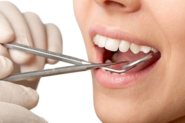 Zęby kobiety i lusterko w ustach dentysty na tle