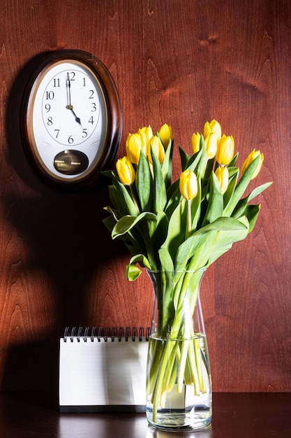 Zegar ścienny pusty kalendarz i tulipany w wazonie