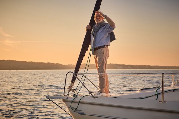 Żeglarski mężczyzna na jachcie elegancki starszy mężczyzna stojący na boku pływającej żaglówki lub pokładu jachtu