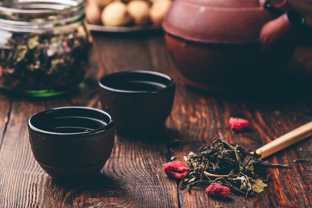 Żeliwne czarki z imbirem i drewnianą łyżką malinowej herbaty ziołowej