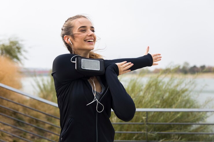 Zdjęcie żeńska atleta rozciąga jej ręki podczas gdy słuchający muzyka outdoors