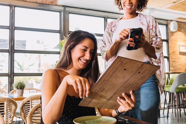 Żeńska kelnerka bierze rozkaz na smartphone w restauraci